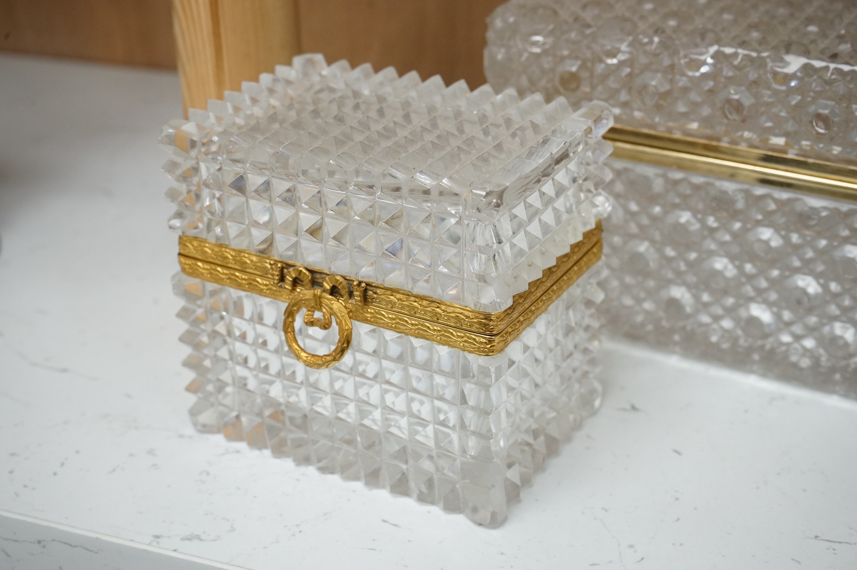 A deeply cut rectangular glass casket, a similar smaller casket and a cylindrical container, all with gilt metal mounts, largest 18cm wide x 10.5cm high.